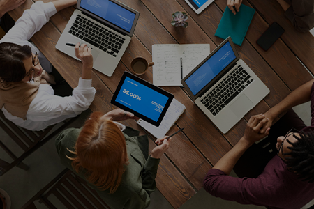 A group of people sitting around a table with laptops.