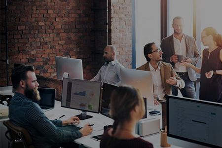 A group of people sitting at tables with computers.